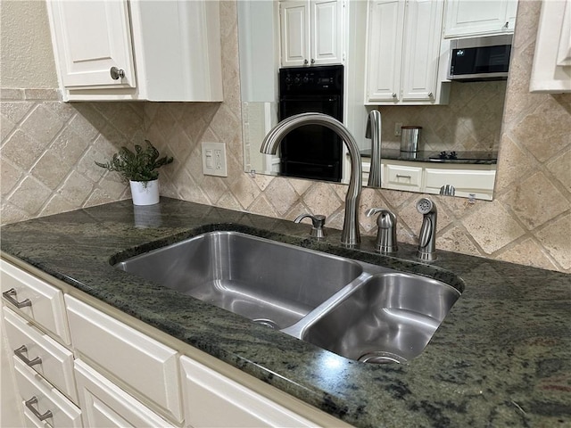 kitchen featuring black appliances, sink, dark stone countertops, tasteful backsplash, and white cabinetry