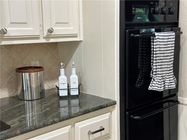 kitchen with backsplash, oven, white cabinets, and dark stone counters