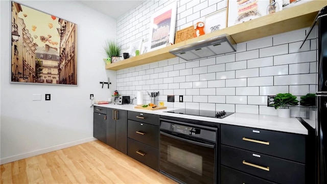 kitchen featuring backsplash, light wood-type flooring, and black appliances