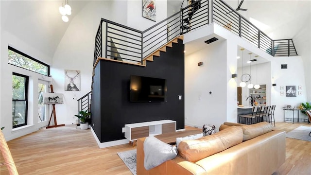 living room with a towering ceiling and light wood-type flooring