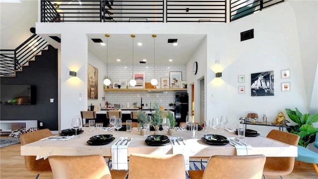 dining space with a towering ceiling and light hardwood / wood-style floors