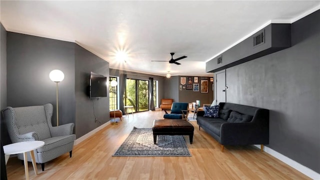 living room featuring ceiling fan, ornamental molding, and light hardwood / wood-style flooring