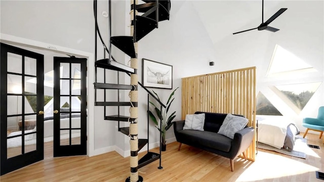 stairs featuring hardwood / wood-style flooring, french doors, ceiling fan, and a high ceiling