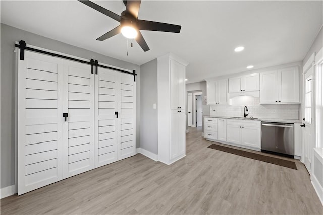 kitchen featuring sink, light hardwood / wood-style flooring, stainless steel dishwasher, backsplash, and white cabinets