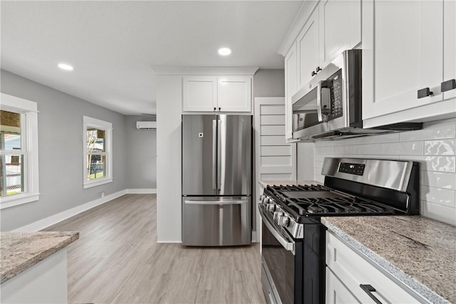 kitchen with decorative backsplash, appliances with stainless steel finishes, light stone countertops, light hardwood / wood-style flooring, and white cabinets