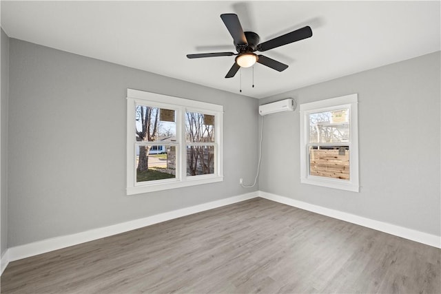 spare room with a wall mounted air conditioner, wood-type flooring, and ceiling fan