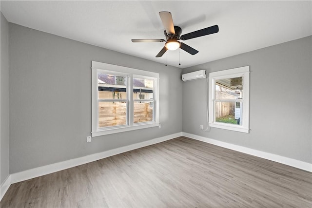 unfurnished room with a wall mounted AC, ceiling fan, and hardwood / wood-style floors