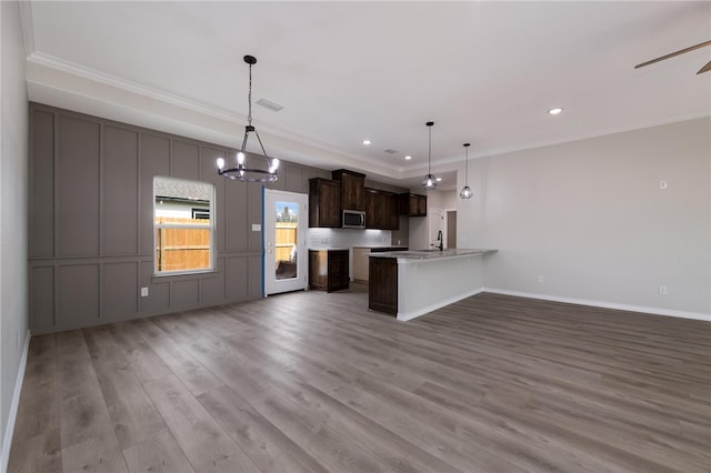 kitchen featuring sink, kitchen peninsula, hanging light fixtures, and light hardwood / wood-style flooring