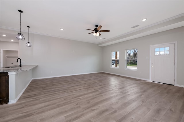 unfurnished living room with sink, light wood-type flooring, and crown molding