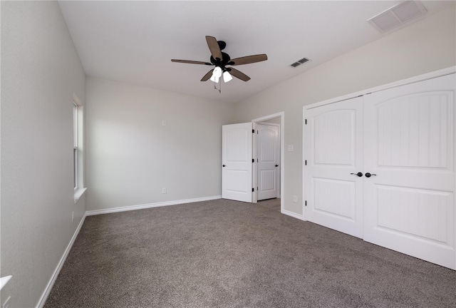 unfurnished bedroom with ceiling fan, a closet, and dark carpet