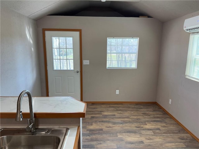 interior space featuring sink, dark wood-type flooring, a wall mounted AC, and vaulted ceiling