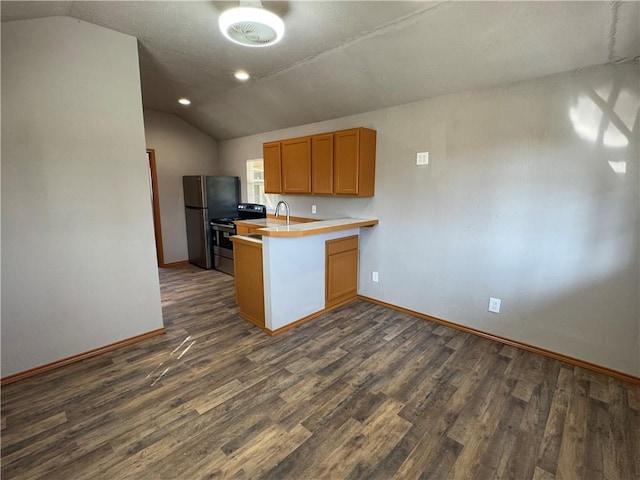 kitchen featuring vaulted ceiling, stainless steel refrigerator, sink, kitchen peninsula, and dark wood-type flooring