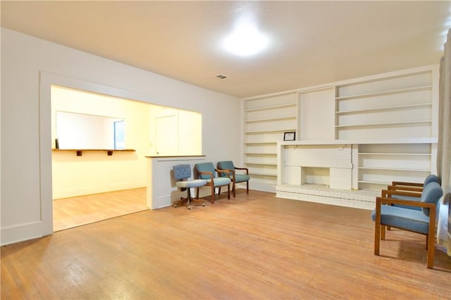 sitting room with hardwood / wood-style floors and a brick fireplace