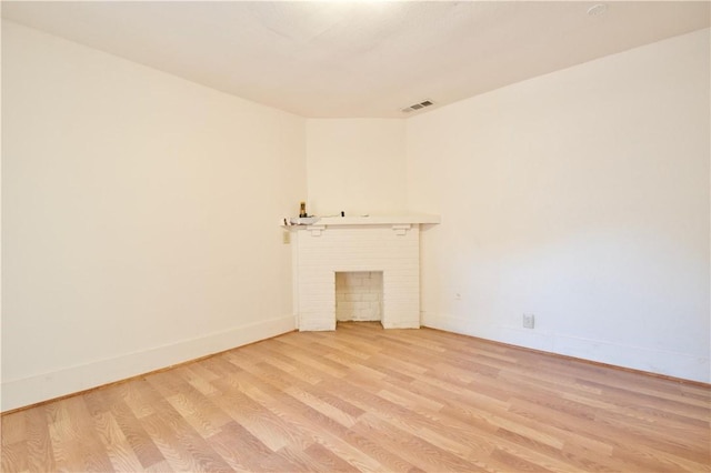 unfurnished living room with a fireplace and light wood-type flooring