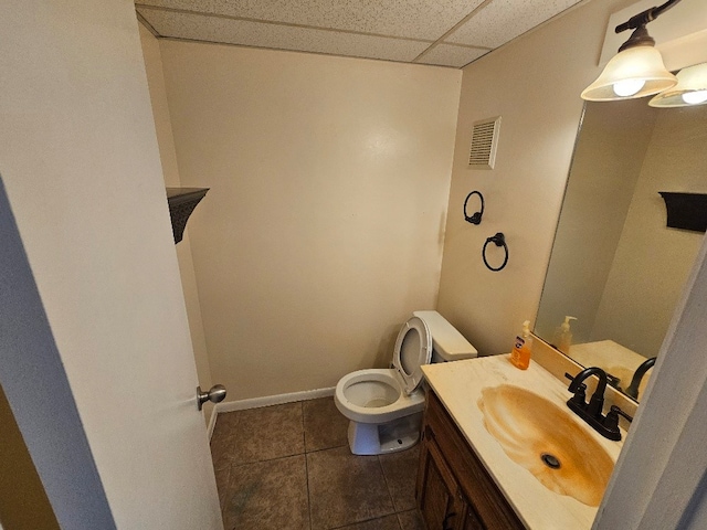 bathroom featuring toilet, vanity, a paneled ceiling, and tile patterned floors