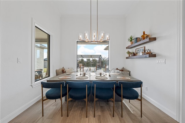 dining room with light wood-type flooring, ornamental molding, and an inviting chandelier