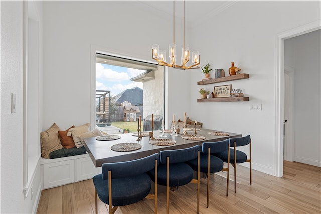 dining room with a chandelier, light wood-type flooring, and crown molding