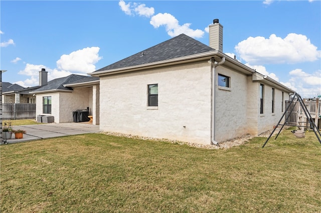 back of property with a lawn, a patio area, and a playground