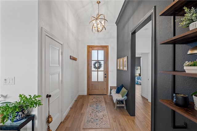 foyer with a notable chandelier, crown molding, and light hardwood / wood-style flooring