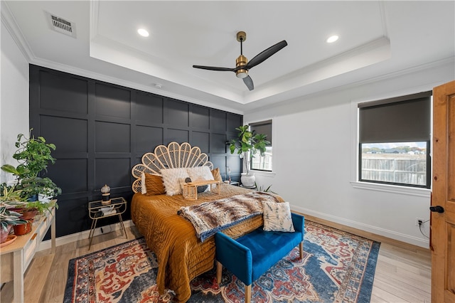 bedroom featuring a raised ceiling, multiple windows, and ceiling fan