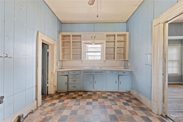 kitchen with wooden walls, gray cabinets, and sink