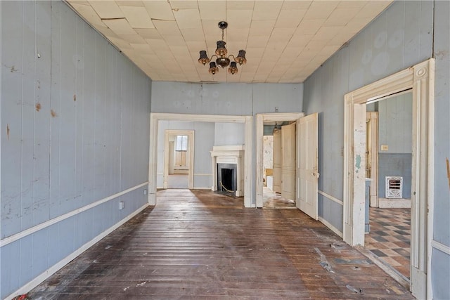 corridor featuring dark wood-type flooring, heating unit, and a chandelier