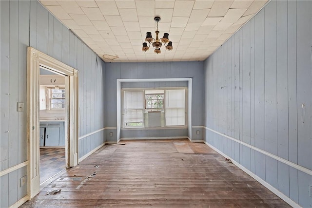 unfurnished room with a healthy amount of sunlight, a chandelier, and light wood-type flooring