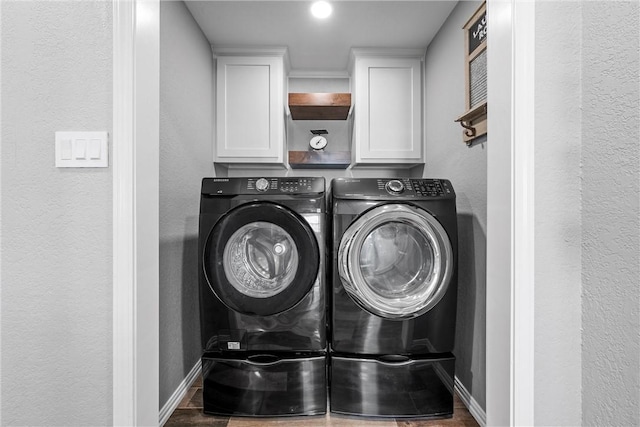 clothes washing area with separate washer and dryer and cabinets