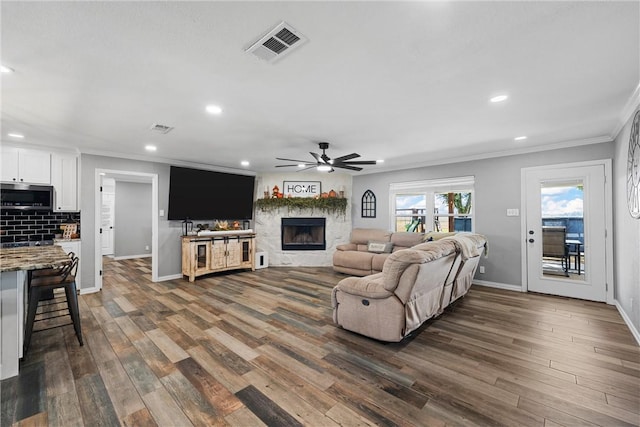 living room with ceiling fan, dark hardwood / wood-style flooring, and crown molding