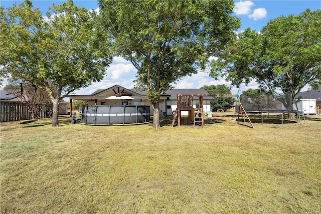 view of yard with a trampoline, a playground, and a covered pool