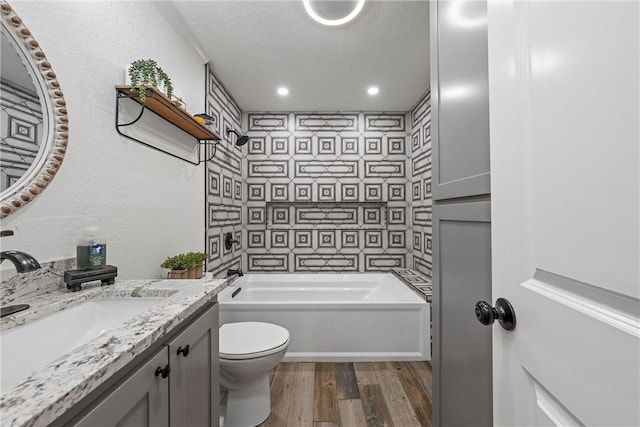 full bathroom featuring a textured ceiling, toilet, shower / washtub combination, vanity, and hardwood / wood-style flooring