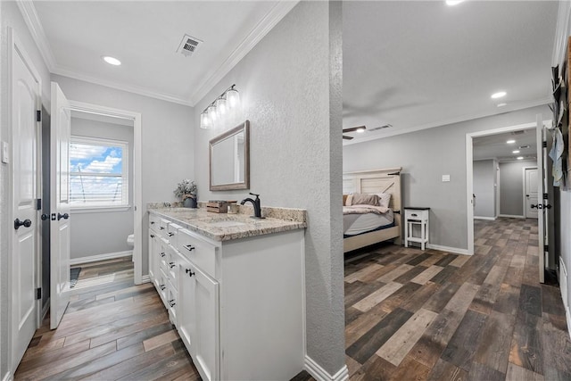 bathroom with wood-type flooring, vanity, toilet, and crown molding