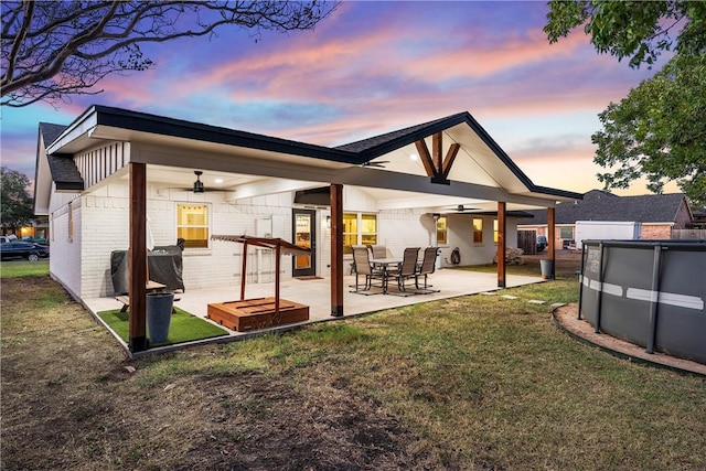 back of property featuring ceiling fan, a yard, and a patio