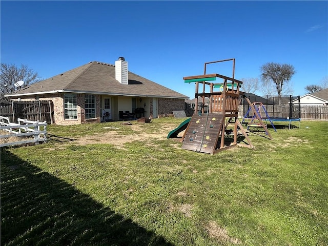 exterior space featuring a trampoline, a playground, fence, and a lawn