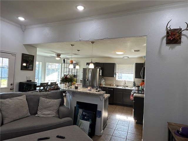 kitchen featuring stainless steel fridge with ice dispenser, open floor plan, ornamental molding, backsplash, and light stone countertops