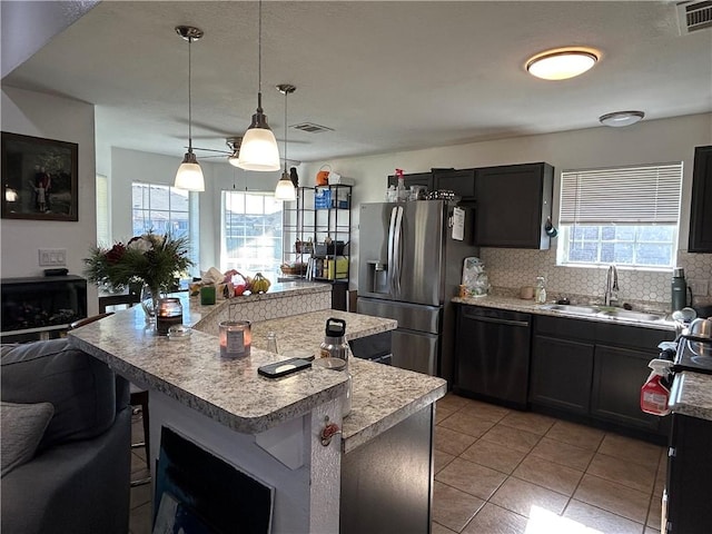 kitchen featuring a breakfast bar area, a sink, black dishwasher, stainless steel fridge with ice dispenser, and decorative light fixtures