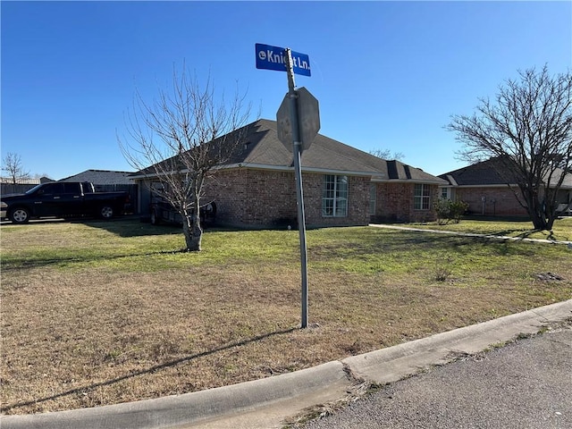 view of side of property featuring brick siding and a yard