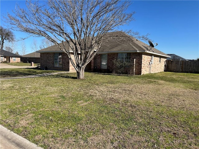 exterior space featuring brick siding, fence, and a front yard