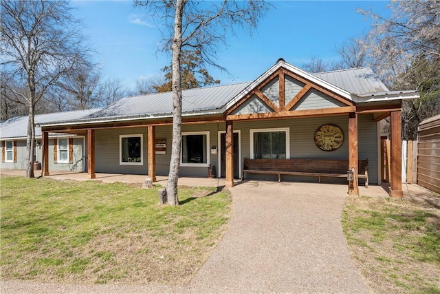 view of front of property with covered porch, metal roof, and a front yard