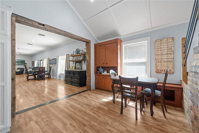 dining room with ornamental molding, visible vents, vaulted ceiling, and light wood-style flooring