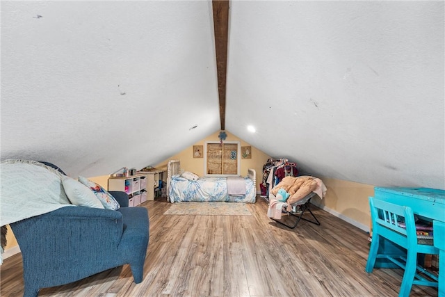 bedroom with lofted ceiling with beams, wood finished floors, and baseboards