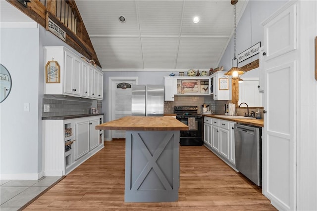 kitchen featuring open shelves, butcher block countertops, a sink, and appliances with stainless steel finishes