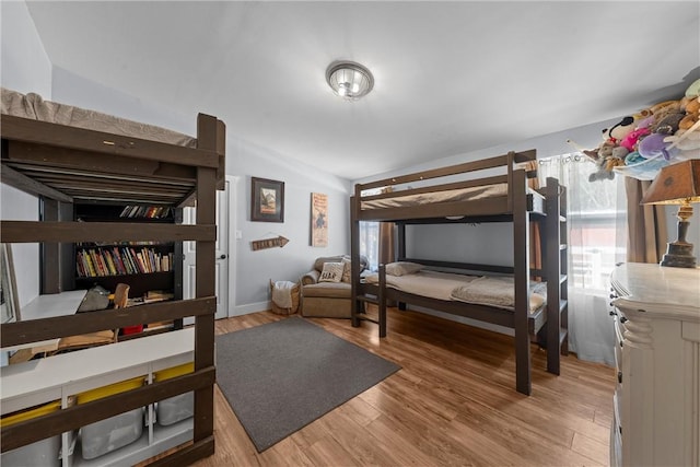 bedroom with vaulted ceiling and wood finished floors