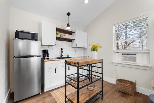 kitchen featuring lofted ceiling, wood counters, stainless steel appliances, open shelves, and a sink