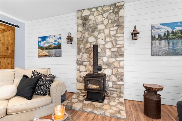 living area featuring wood finished floors, a wood stove, and a barn door