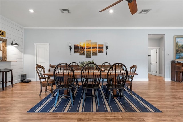 dining space featuring crown molding, visible vents, ceiling fan, and wood finished floors