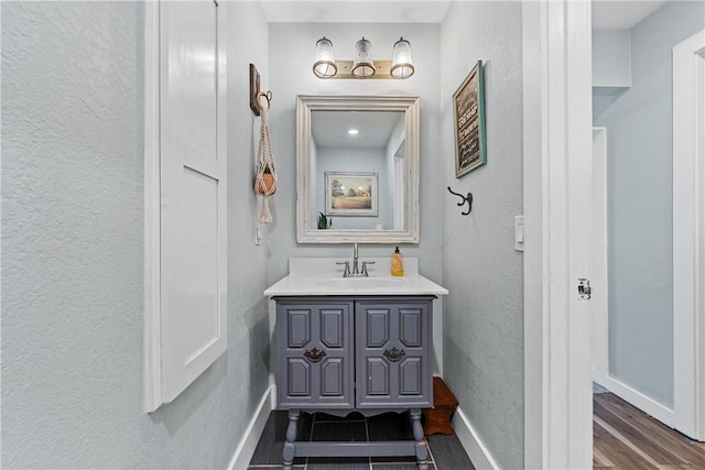 bathroom featuring a textured wall, wood finished floors, vanity, and baseboards