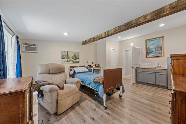 bedroom featuring light wood finished floors, recessed lighting, an AC wall unit, a sink, and beamed ceiling