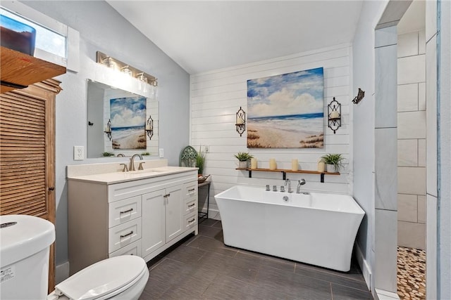 bathroom featuring toilet, a soaking tub, and vanity