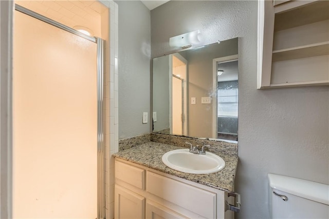 bathroom with vanity, a shower with shower door, and toilet